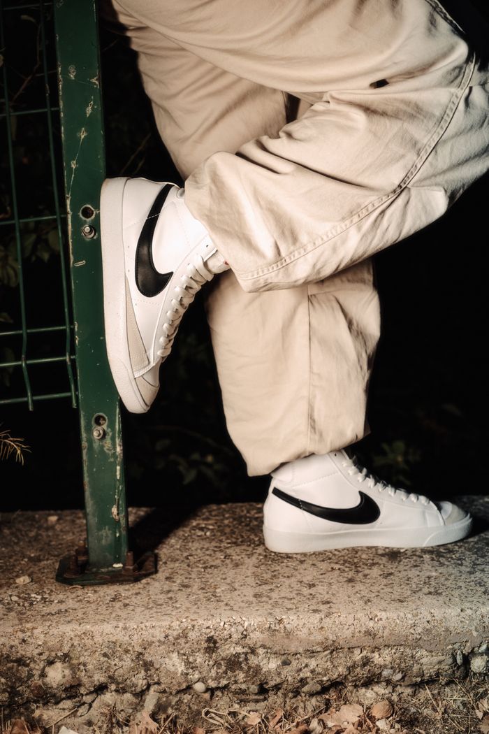 Crafting Captivating Headlines: Your awesome post title goes here Close-up of white Nike shoes leaning against a rail, highlighting trendy casual style.