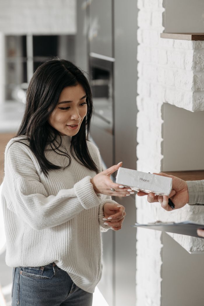 Mastering the First Impression: Your intriguing post title goes here A woman happily receives a parcel indoors, showcasing a moment of excitement and anticipation.